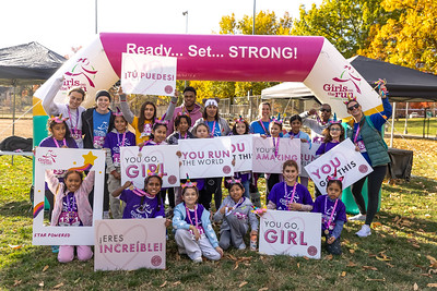 A Girls on the Run participant smiling and high fiving her coaches with the rest of her team smiling and cheering behind her.