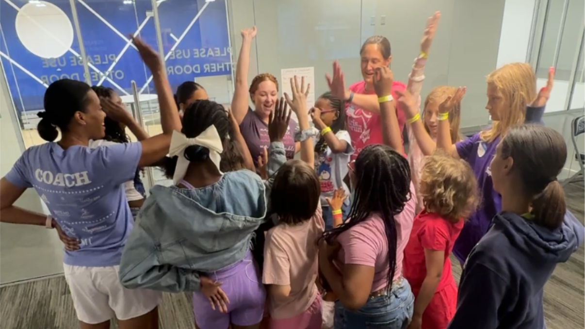 Group of Girls on the Run participants and coaches doing a cheer at Camp GOTR.
